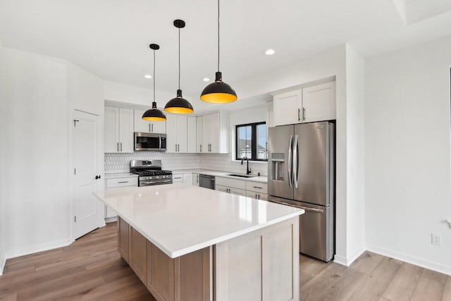 kitchen with white cabinetry, a center island, stainless steel appliances, and light wood-type flooring