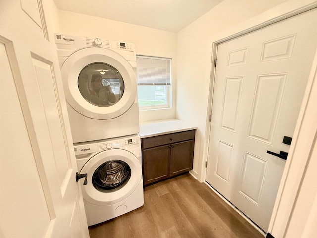 laundry room with cabinets, light hardwood / wood-style floors, and stacked washer / drying machine