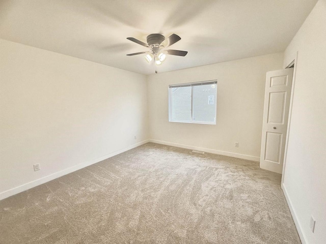 spare room featuring light colored carpet and ceiling fan