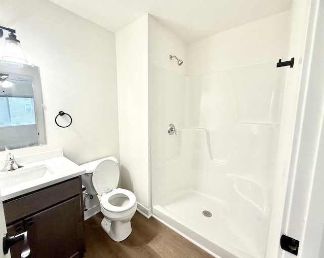 bathroom with hardwood / wood-style floors, toilet, a shower, and vanity