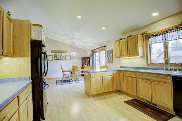 kitchen featuring pendant lighting, lofted ceiling, black appliances, sink, and light wood-type flooring