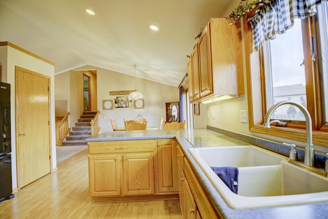 kitchen with kitchen peninsula, sink, light hardwood / wood-style flooring, hanging light fixtures, and lofted ceiling