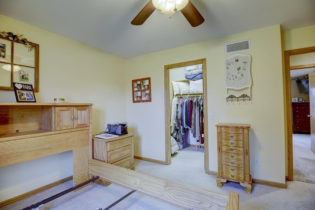 carpeted bedroom featuring a walk in closet, a closet, and ceiling fan