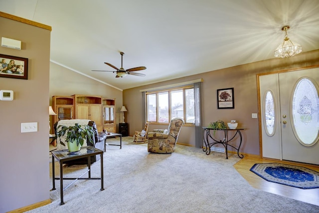 carpeted foyer with ceiling fan with notable chandelier, vaulted ceiling, and crown molding