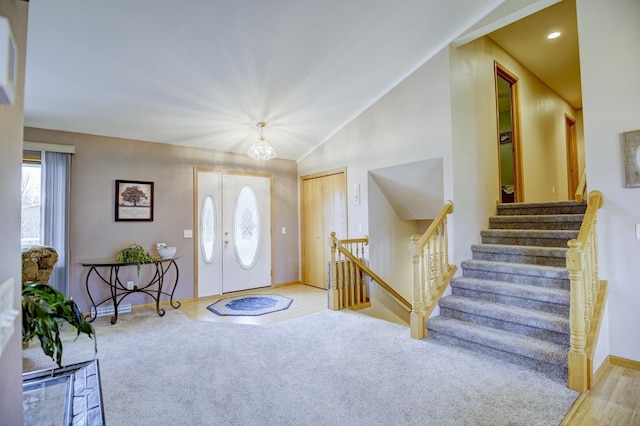 entrance foyer featuring french doors, high vaulted ceiling, light hardwood / wood-style floors, and an inviting chandelier