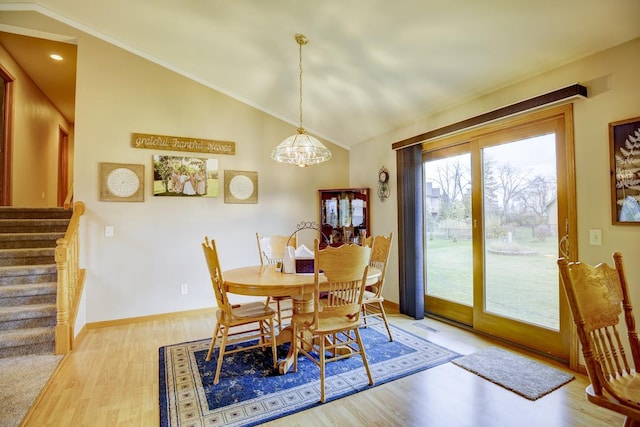 dining space featuring a notable chandelier, light wood-type flooring, and lofted ceiling