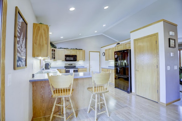 kitchen with kitchen peninsula, black appliances, light hardwood / wood-style flooring, lofted ceiling, and a breakfast bar area