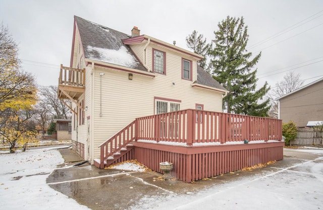 rear view of property featuring a balcony and a wooden deck