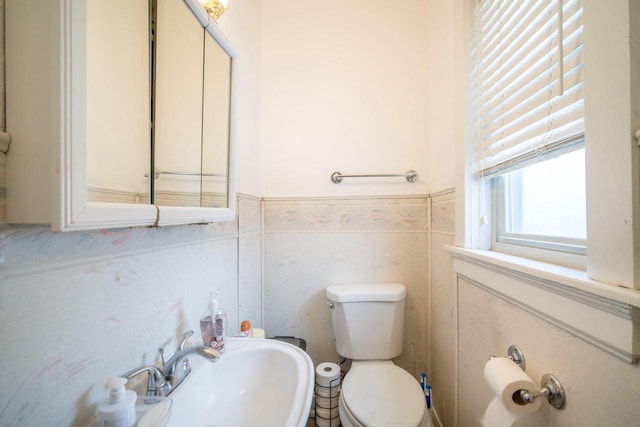 bathroom with sink, tile walls, and toilet