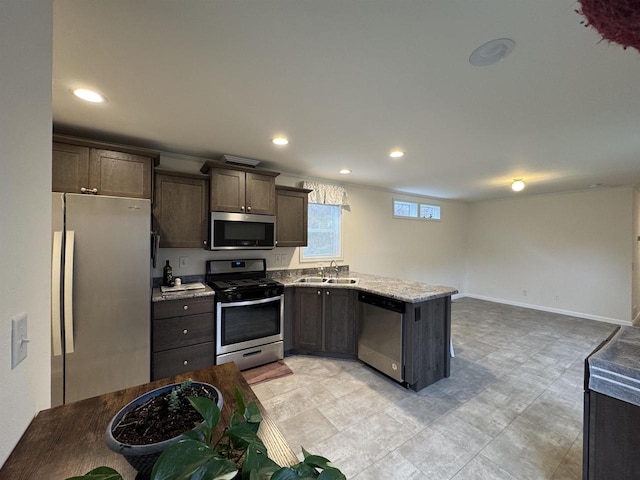 kitchen featuring light stone counters, sink, dark brown cabinetry, and stainless steel appliances