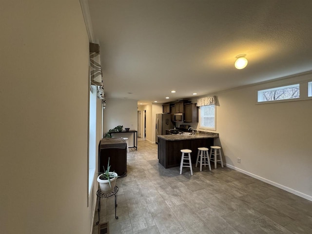 kitchen featuring dark brown cabinets, kitchen peninsula, a breakfast bar area, and appliances with stainless steel finishes