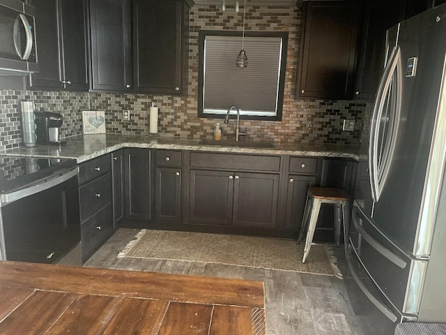 kitchen featuring backsplash, dark wood-type flooring, hanging light fixtures, sink, and appliances with stainless steel finishes