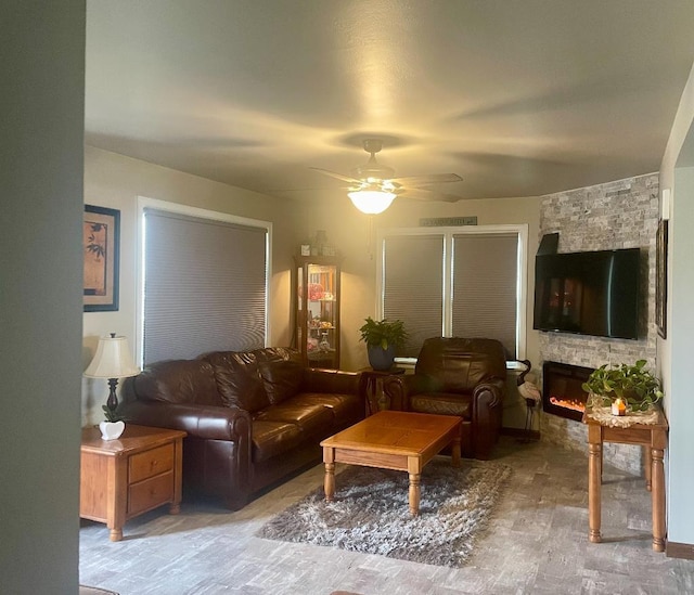 living room with a stone fireplace and ceiling fan