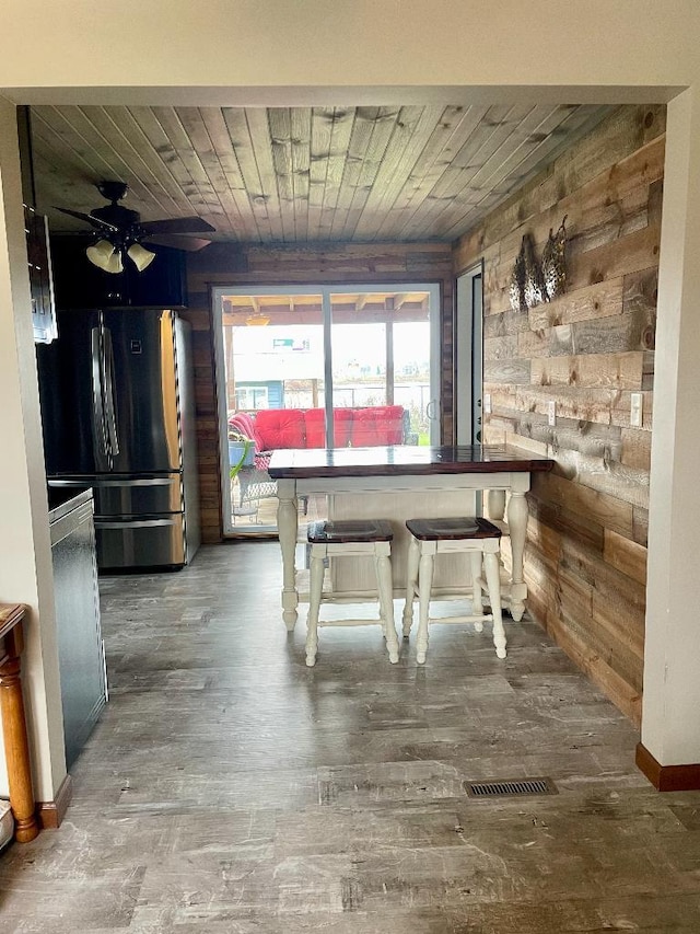 unfurnished dining area with hardwood / wood-style flooring, ceiling fan, wooden ceiling, and wooden walls