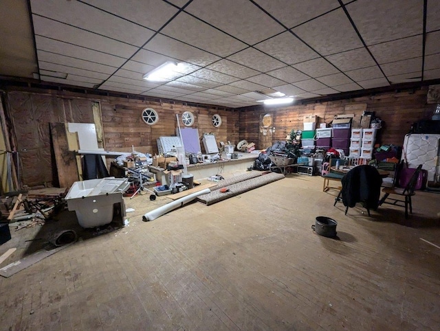 workout room featuring wood walls, hardwood / wood-style floors, and a drop ceiling