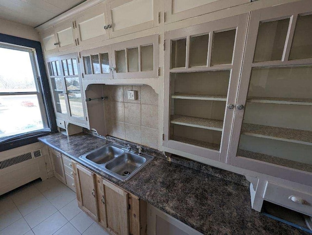 kitchen featuring radiator heating unit, light tile patterned floors, a healthy amount of sunlight, and sink