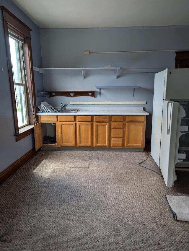 kitchen featuring white fridge, light colored carpet, and sink