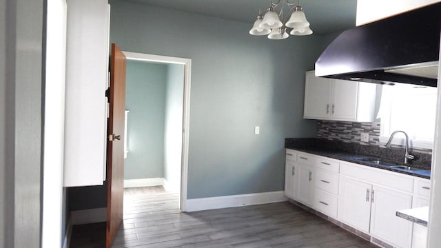 kitchen featuring backsplash, sink, light hardwood / wood-style floors, white cabinetry, and range hood