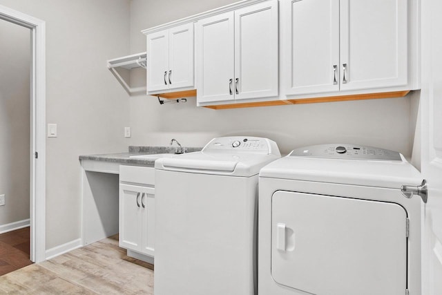 washroom with washing machine and clothes dryer, sink, cabinets, and light wood-type flooring