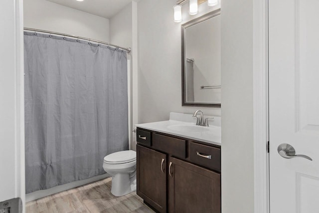 full bathroom featuring hardwood / wood-style floors, vanity, shower / tub combo, and toilet