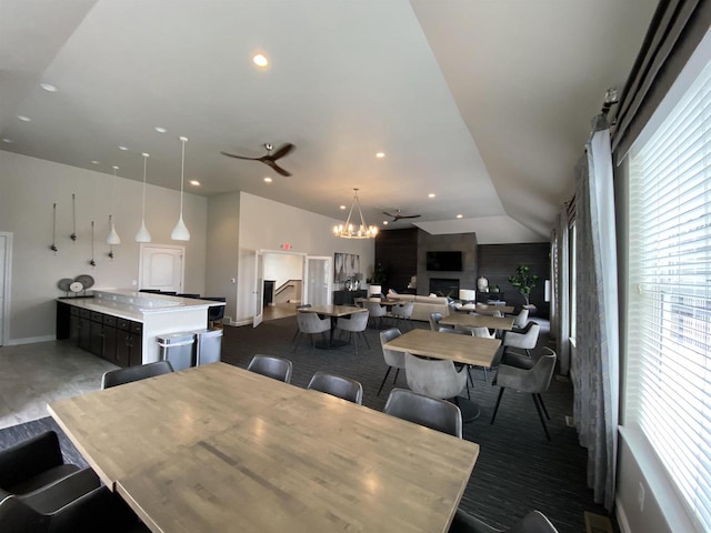 dining space with ceiling fan with notable chandelier and vaulted ceiling