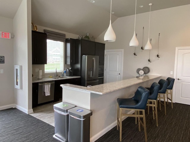 kitchen featuring sink, kitchen peninsula, pendant lighting, a kitchen bar, and appliances with stainless steel finishes