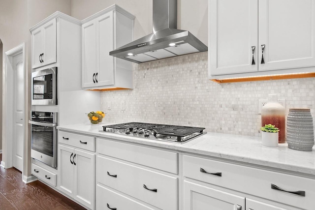 kitchen featuring white cabinets, wall chimney exhaust hood, dark hardwood / wood-style floors, light stone countertops, and appliances with stainless steel finishes