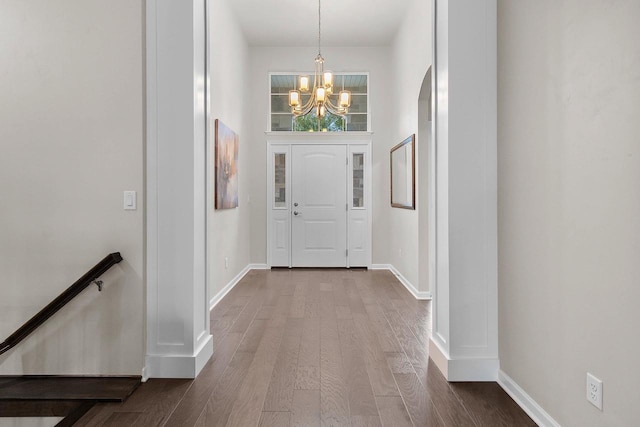 foyer featuring wood-type flooring, a high ceiling, and a notable chandelier