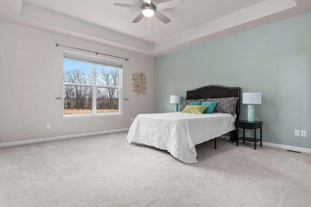 bedroom featuring ceiling fan, carpet floors, and a tray ceiling