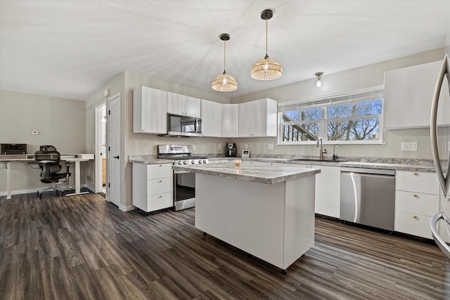 kitchen featuring white cabinets, sink, appliances with stainless steel finishes, decorative light fixtures, and dark hardwood / wood-style flooring