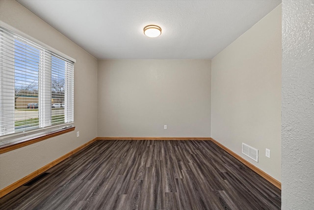 empty room featuring a textured ceiling and dark hardwood / wood-style floors