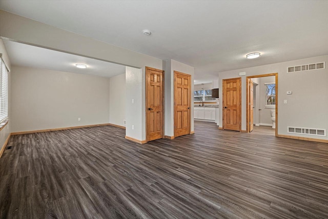 unfurnished living room with a wealth of natural light and dark wood-type flooring