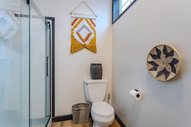 bathroom featuring toilet, wood-type flooring, and a shower with door