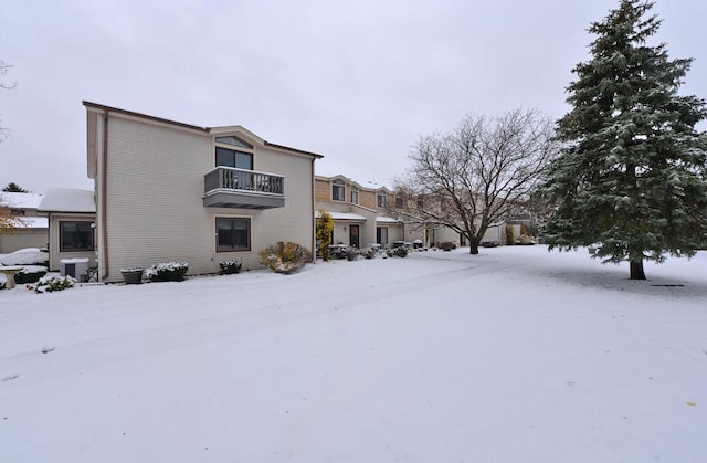 snow covered property with cooling unit and a balcony