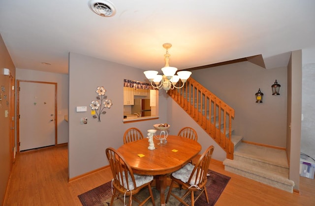 dining space with light hardwood / wood-style flooring and a chandelier