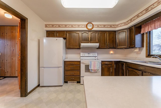 kitchen with dark brown cabinetry, sink, and white appliances