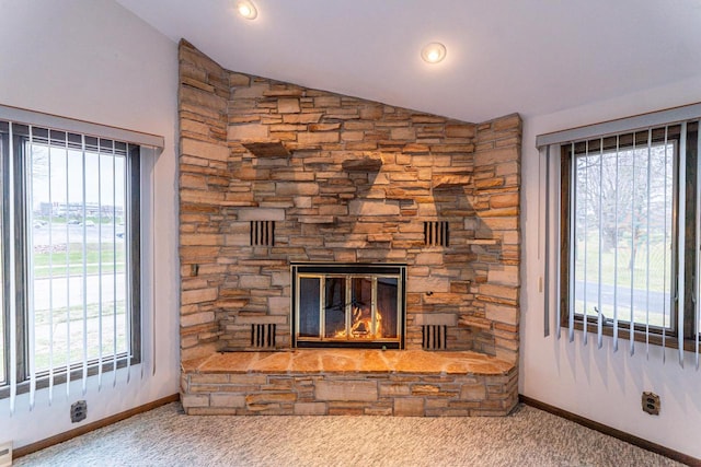 unfurnished living room with a stone fireplace, plenty of natural light, and lofted ceiling