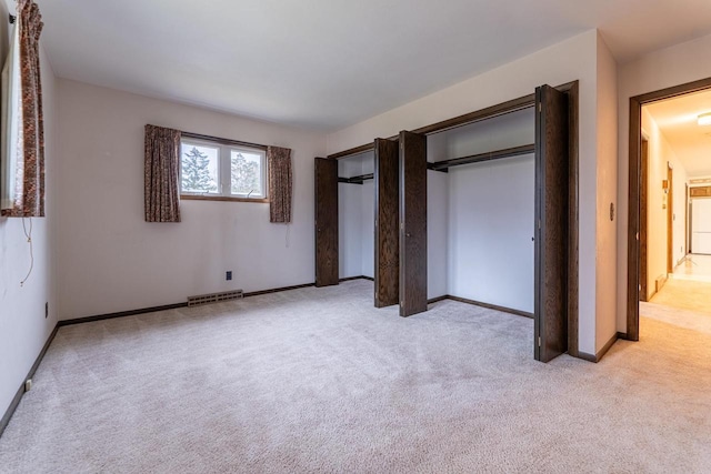 unfurnished bedroom featuring a closet and light colored carpet