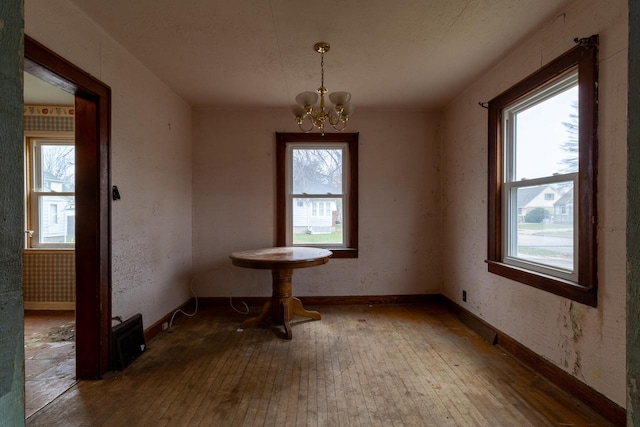 unfurnished dining area featuring a chandelier and hardwood / wood-style flooring