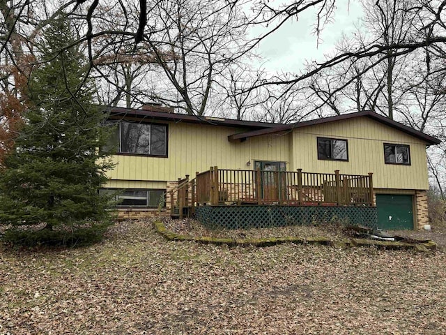 rear view of property with a garage and a wooden deck