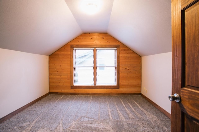 bonus room featuring wood walls, carpet floors, and vaulted ceiling