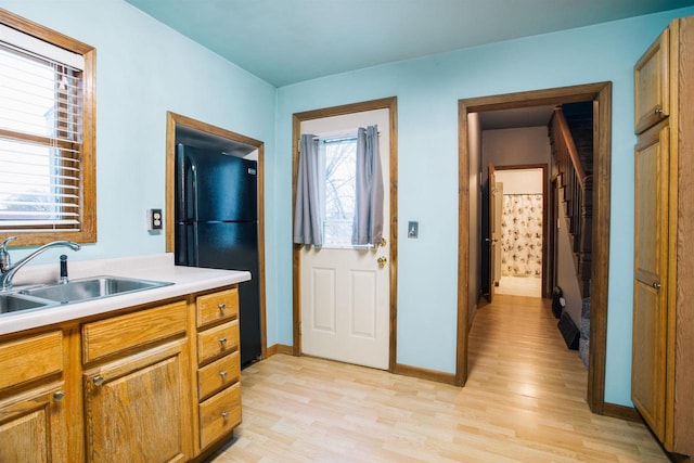 kitchen featuring black fridge, light wood-type flooring, and sink