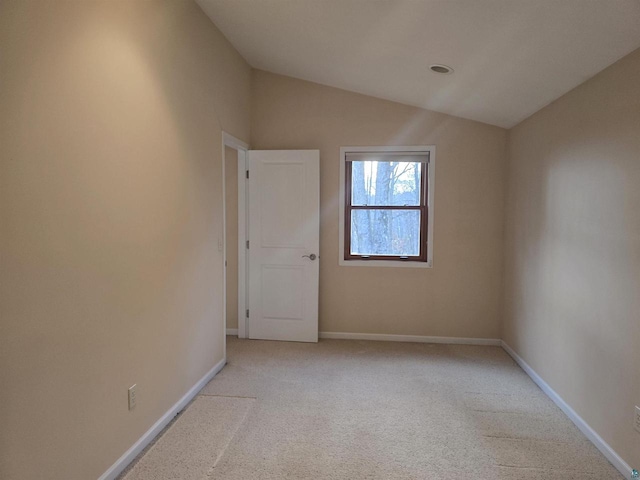 carpeted spare room featuring vaulted ceiling