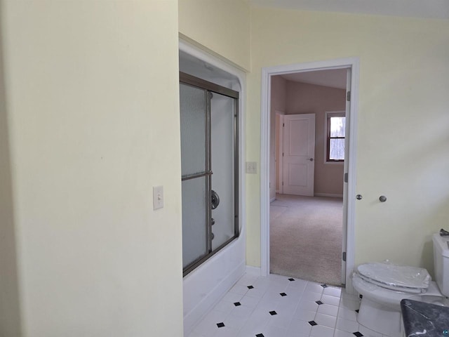 bathroom featuring toilet, lofted ceiling, and bath / shower combo with glass door