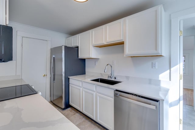 kitchen with light stone countertops, stainless steel appliances, sink, light hardwood / wood-style flooring, and white cabinetry