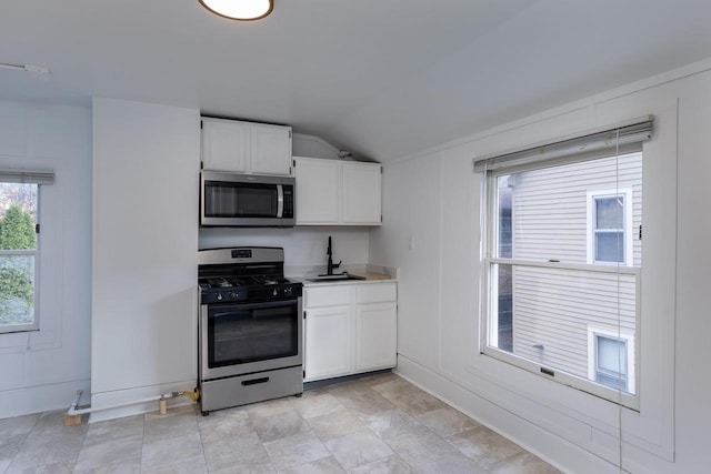 kitchen with white cabinets, stainless steel appliances, lofted ceiling, and sink