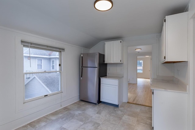 kitchen featuring a wealth of natural light, stainless steel fridge, white cabinets, and lofted ceiling