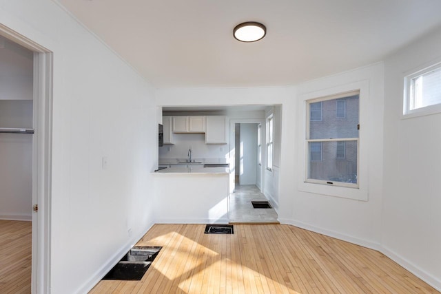 unfurnished living room with sink and light hardwood / wood-style flooring