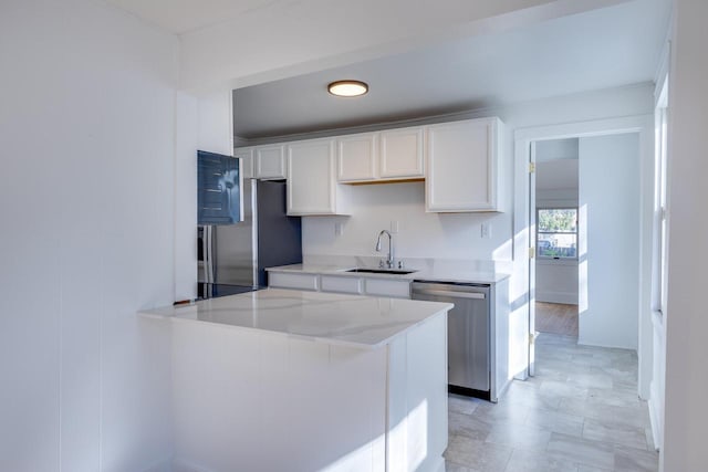 kitchen featuring white cabinets, sink, appliances with stainless steel finishes, light stone counters, and kitchen peninsula