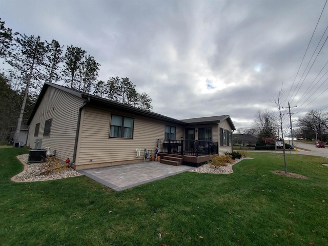 rear view of house featuring a wooden deck, central air condition unit, a yard, and a patio